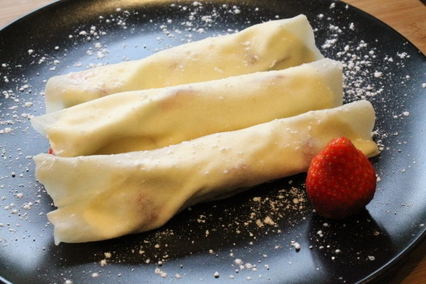 Rolled Peking duck pancakes with strawberries and whipped cream